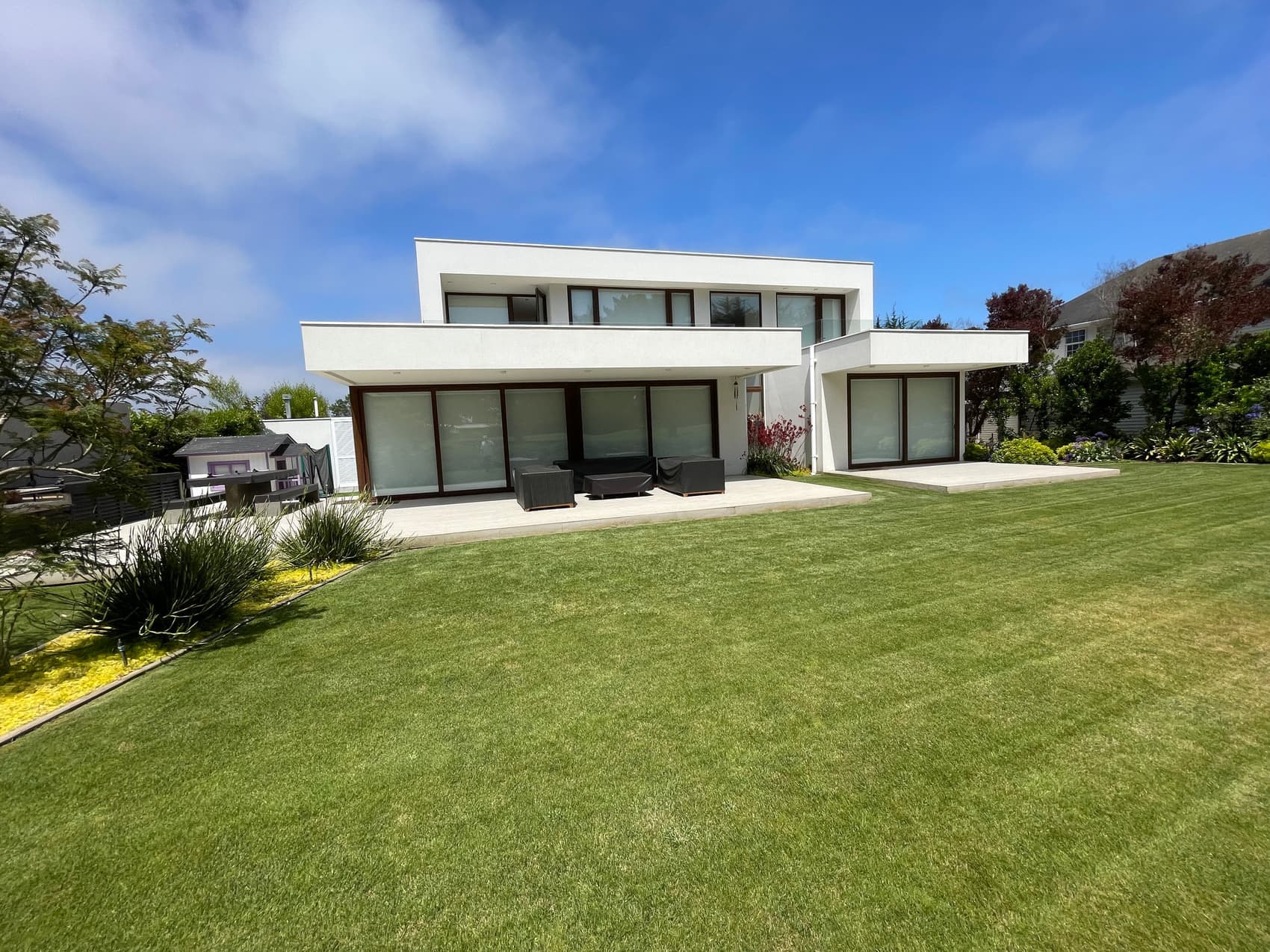 Fachada posterior de casa blanca con jardín